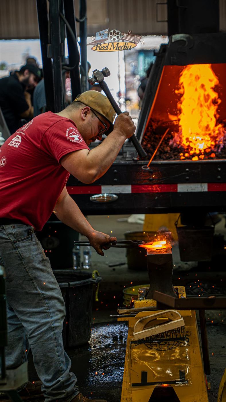 A smith raising his hammer beside the forge