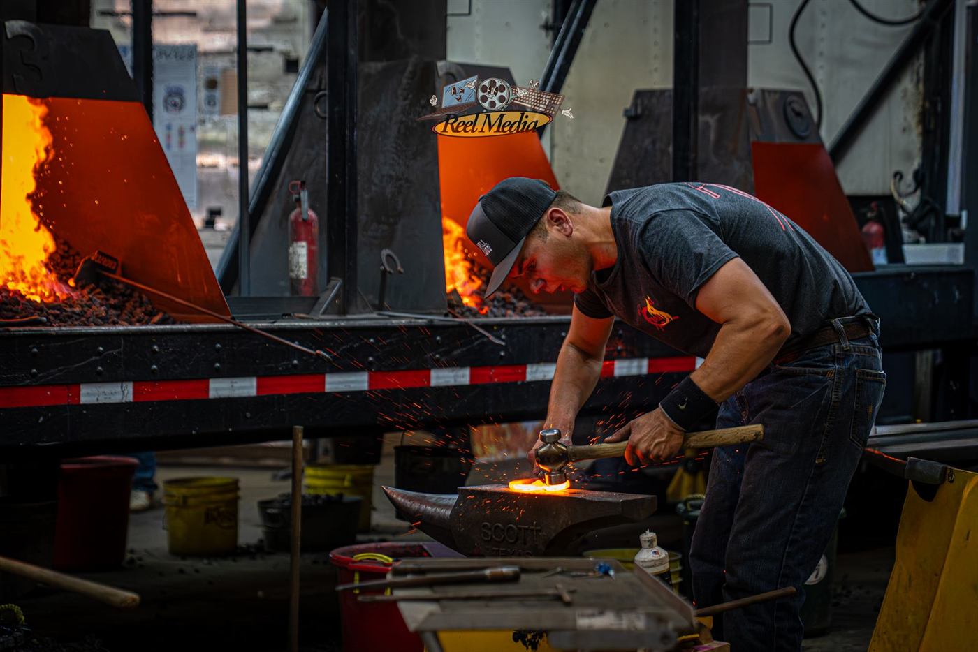 A smith hammering at the anvil in front of the fire