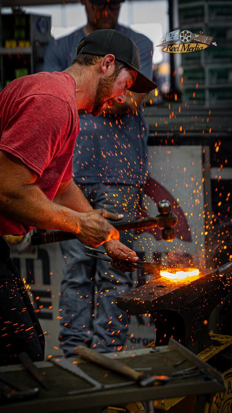 Sparks flying off the anvil as a smith strikes