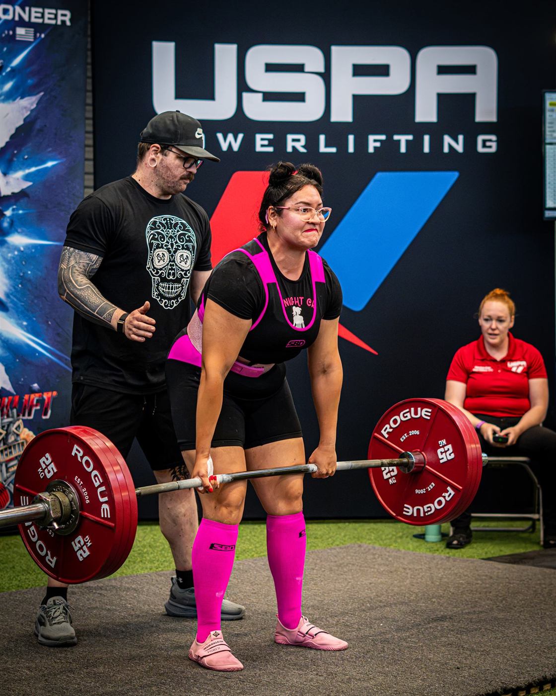 A lifter in pink setting up for a deadlift